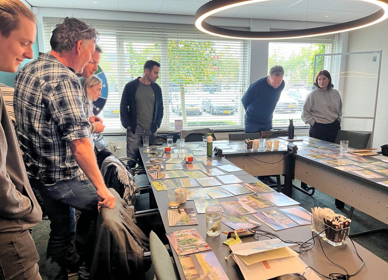 Gemeenteambtenaren met elkaar in gesprek aan een tafel in U vorm met kaarten erop