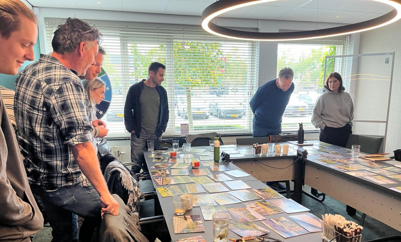 Gemeenteambtenaren met elkaar in gesprek aan een tafel in U vorm met kaarten erop