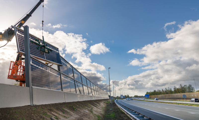 Snelweg waarlangs zonnepanelen worden geplaatst door ene hijskraan