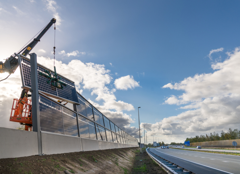 Snelweg waarlangs zonnepanelen worden geplaatst door ene hijskraan