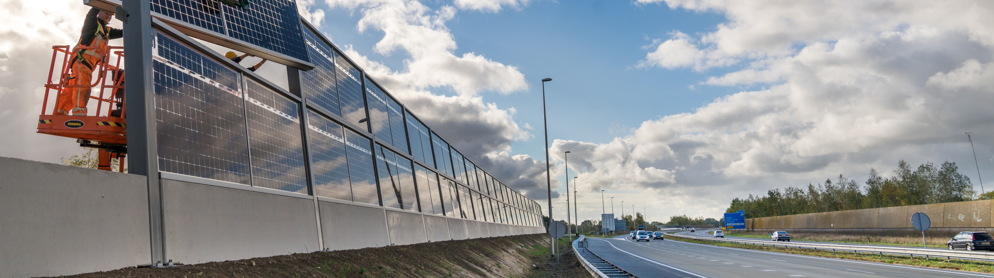 Snelweg waarlangs zonnepanelen worden geplaatst door ene hijskraan