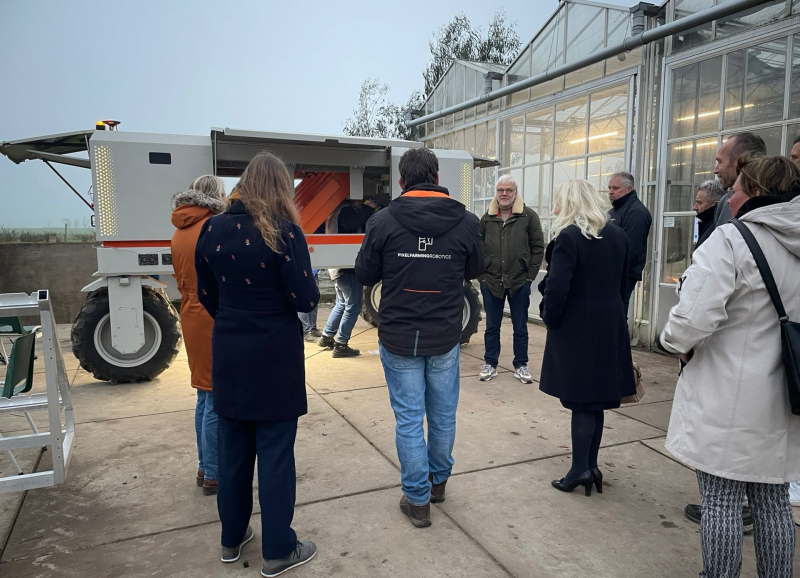 Groepje deelnemers aan de Safaritour staat buiten een kas bij een landbouwrobot