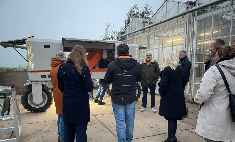 Groepje deelnemers aan de Safaritour staat buiten een kas bij een landbouwrobot