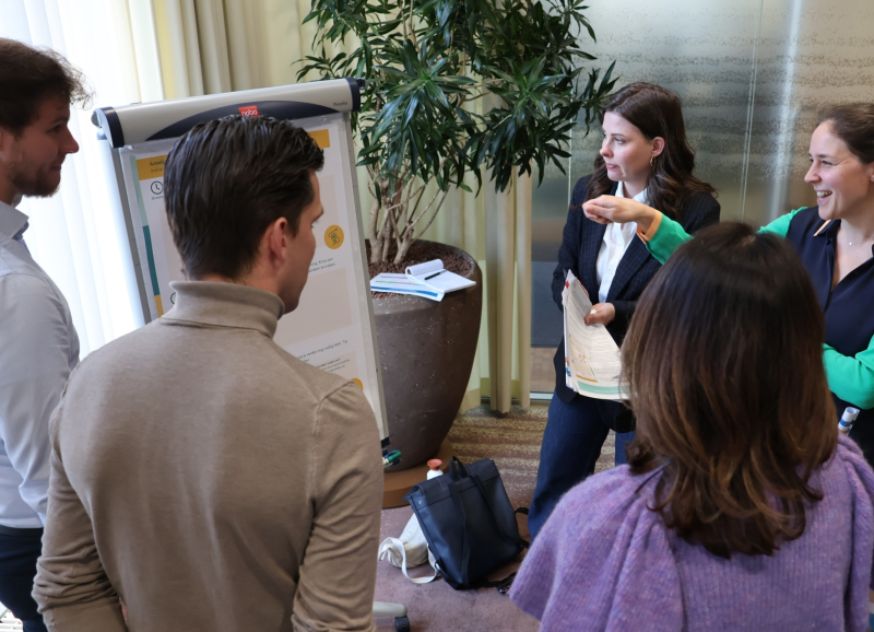 Vijf medewerkers van rijk en regio met elkaar in gesprek bij een flipover