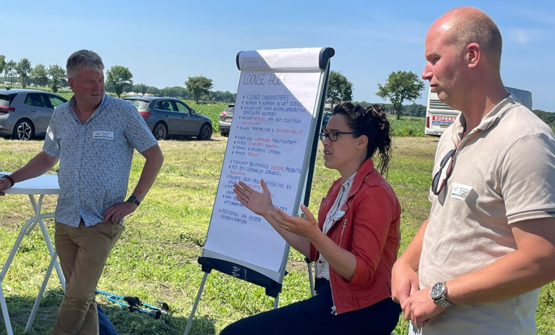 Drie deelnemers aan werkbezoek aan de AgroProeftuin op de proeflocatie met elkaar in gesprek bij een flipover 