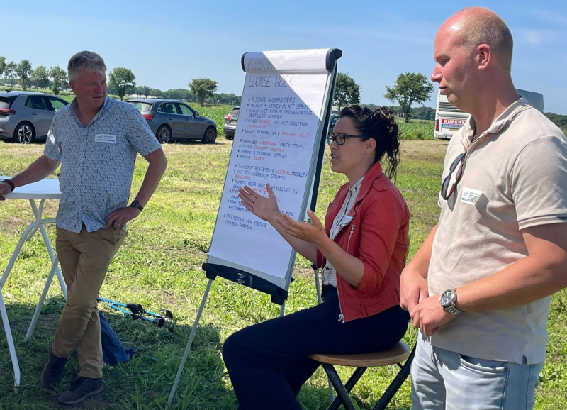 Drie deelnemers aan werkbezoek aan de AgroProeftuin op de proeflocatie met elkaar in gesprek bij een flipover 