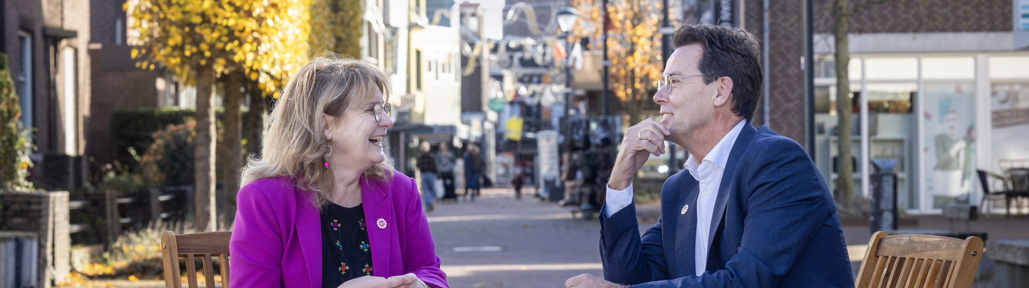 Marieke Moorman en René Peerenboom zitten aan een klein bistrostafeltje met een Brabants kleedje midden in een winkelstraat 