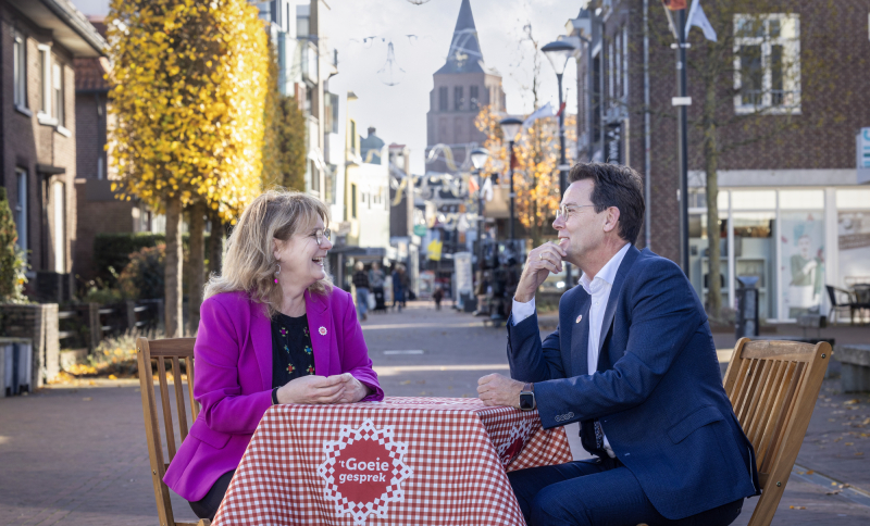 Marieke Moorman en René Peerenboom zitten aan een klein bistrostafeltje met een Brabants kleedje midden in een winkelstraat 