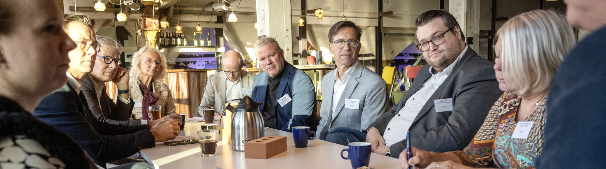 Bestuurders en ondernemers aan tafel met koffie en notitieblokken tijdens de consultatiebijeenkomst