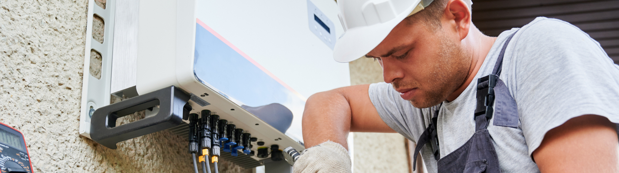 Monteur installeert zonnepanelen-omvormer en sluit kabels aan voor duurzame energievoorziening