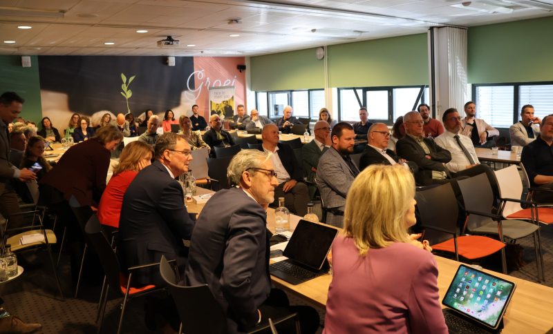 Wethouders en andere bestuurders op de bestuurlijke Regiodag in een vergaderzaal tijdens een presentatie