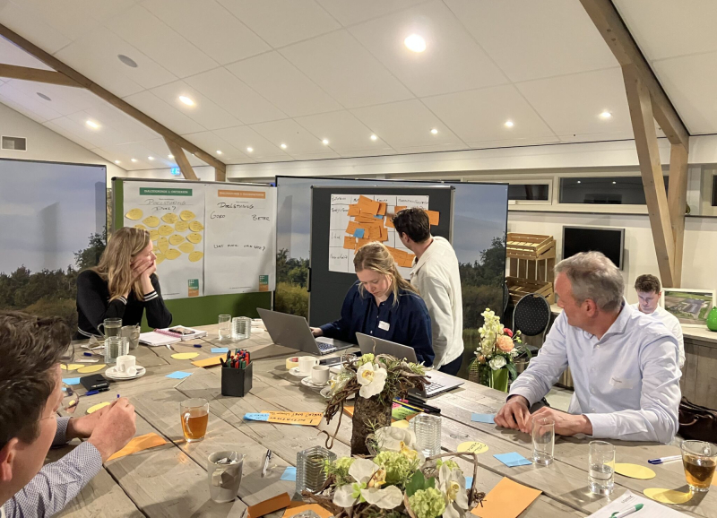Deelnemers aan een vorige NOVEX De Peel werksessie werken samen aan een opdracht met presentaties en post‑its.