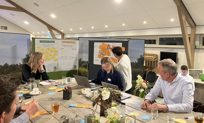 Deelnemers aan een vorige NOVEX De Peel werksessie werken samen aan een opdracht met presentaties en post‑its.