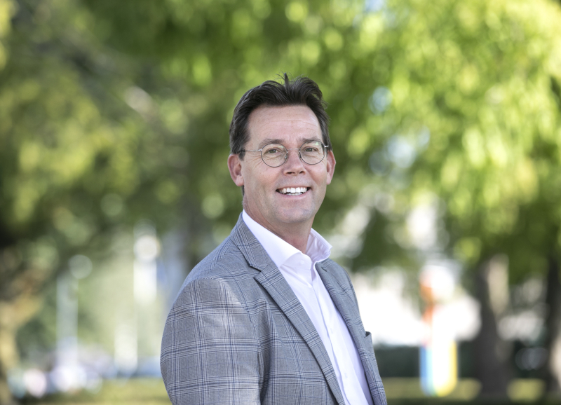 Portretfoto René Peerenboom, buiten met groene bomen op de achtergrond